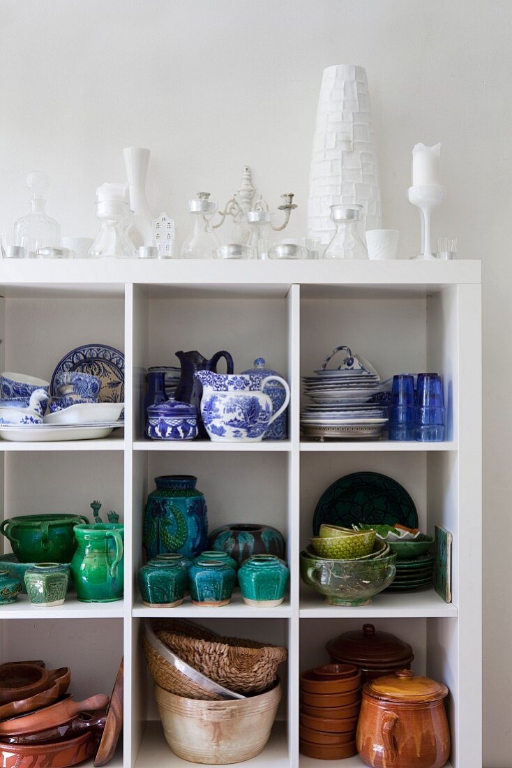 Weisses Regal mit Geschirr aus Keramik und blau-weiß bemaltem Porzellan