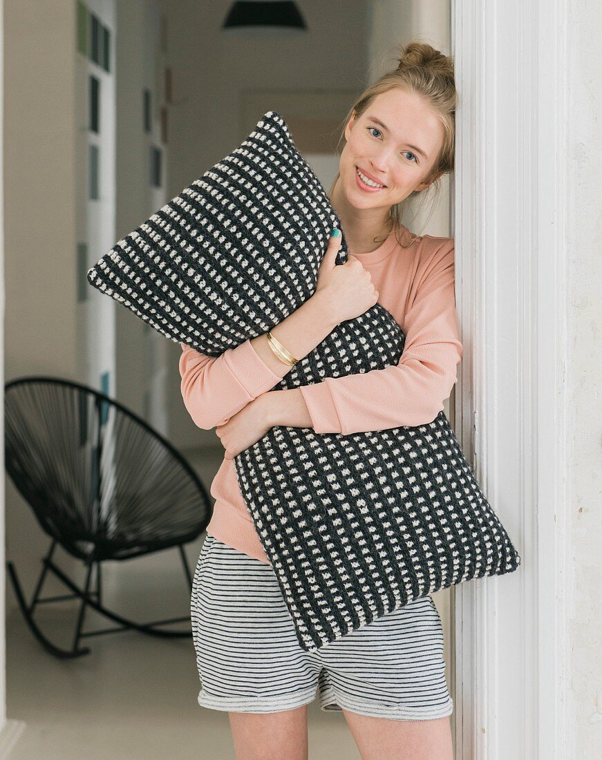 A woman holding a black-and-white cushion knitted in slip stitch