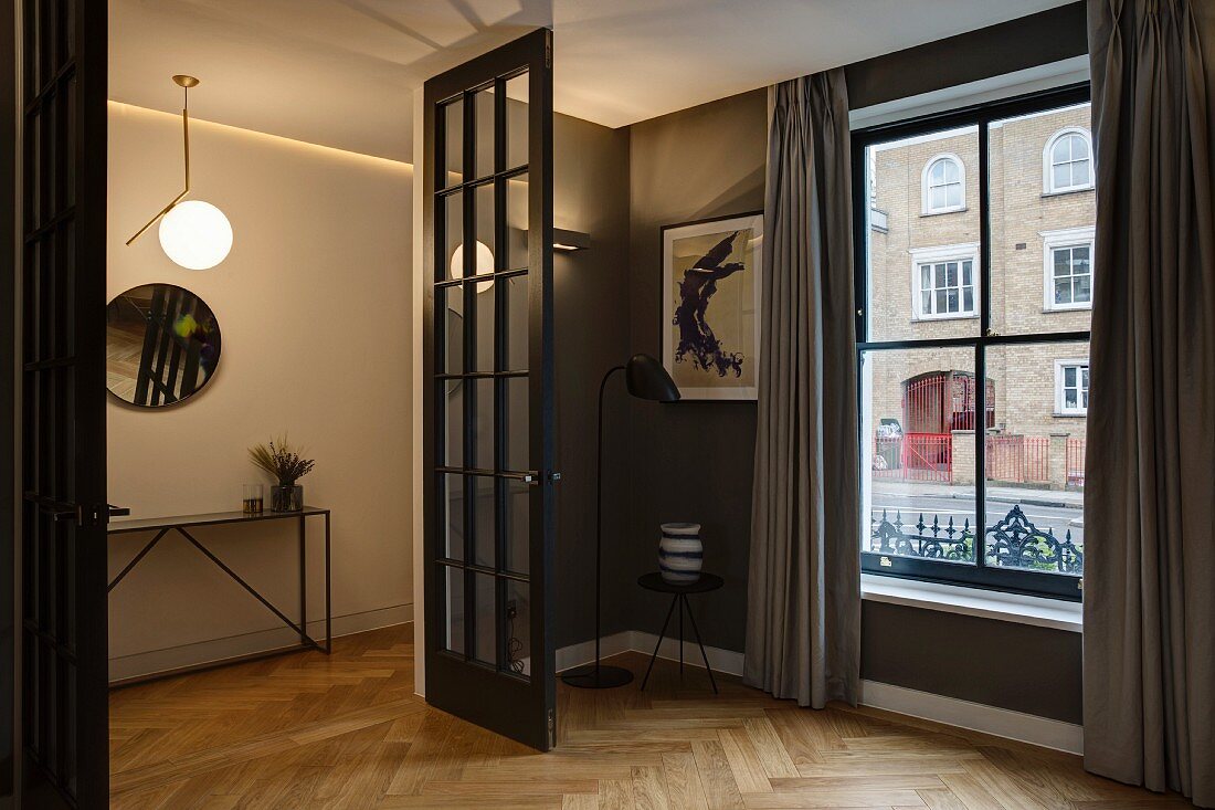 Elegantes Zimmer mit Taupe Wandfarbe und Fischgrätparkett, Blick in Dielenbereich mit Wandspiegel
