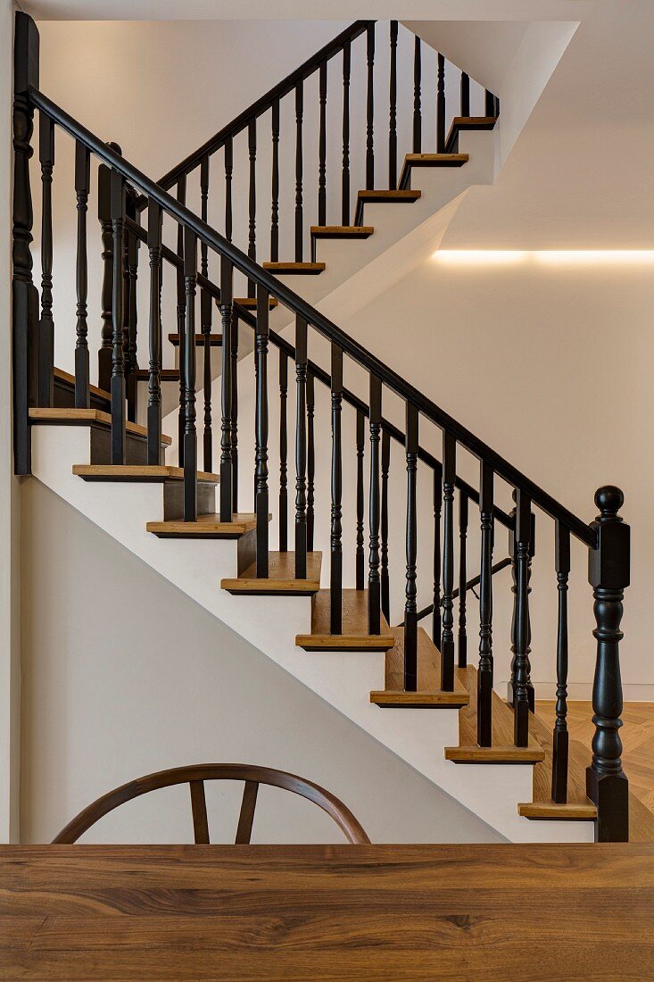 Elegant restaurierte Holztreppe mit schwarz lackiertem Geländer und indirekter Beleuchtung