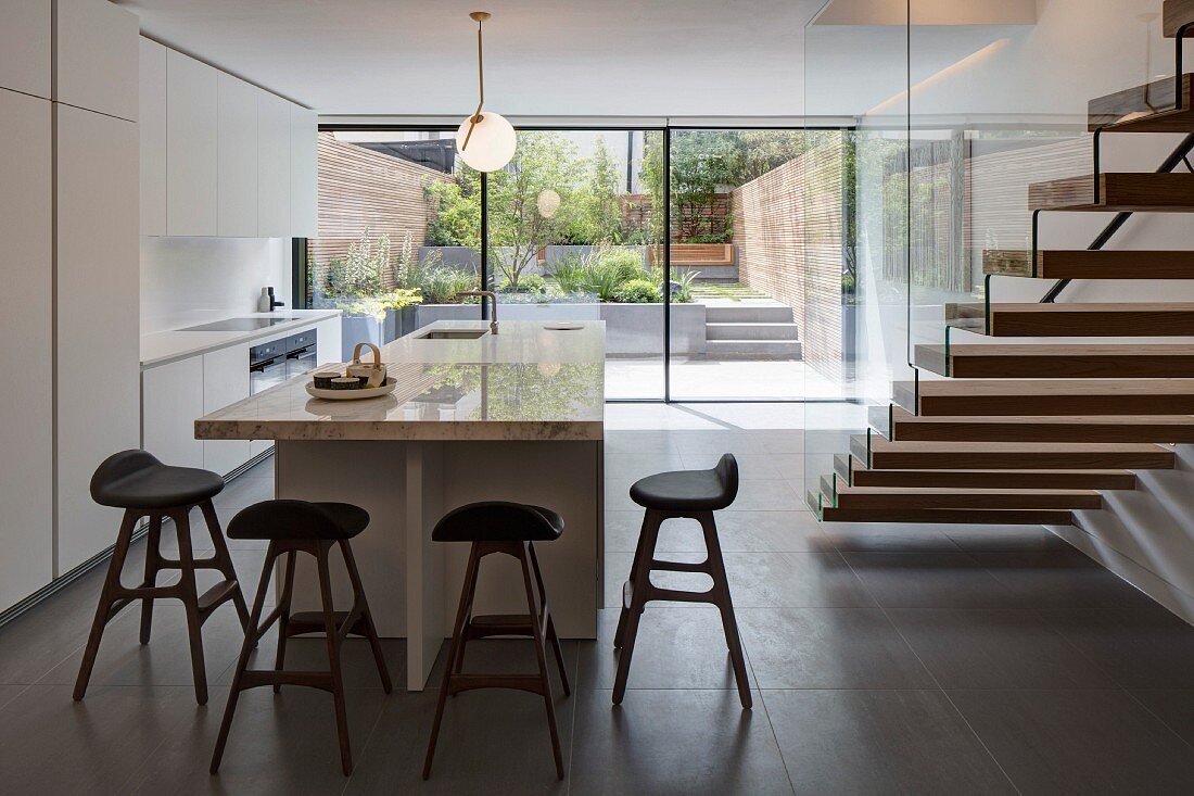 weiße Designerküche mit Küchentheke und Treppenaufgang, Vollverglasung mit Gartenblick