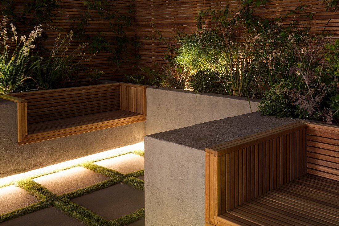 Moderner begrünter Terrassenplatz mit indirekter Beleuchtung und Holz-Sichtschutzwänden