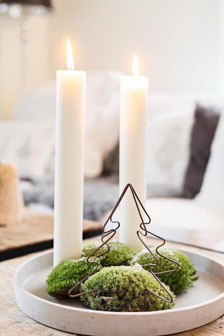 Two lit candles, moss and metal Christmas on tray