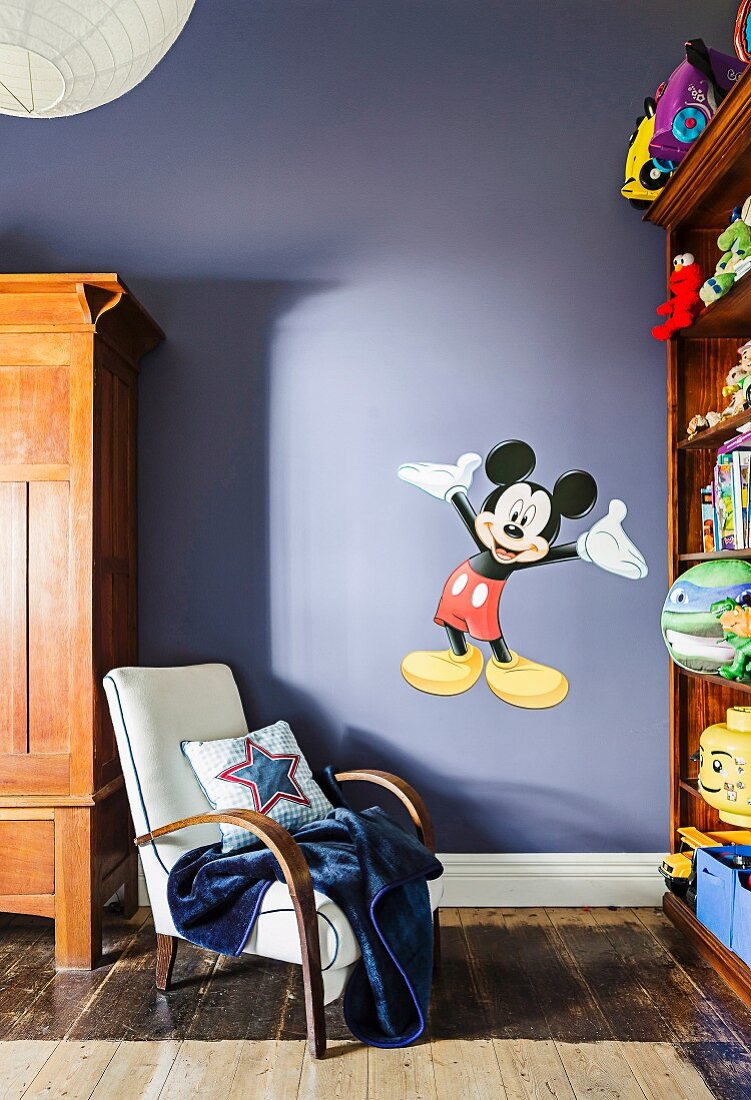 Retro armchair against purple wall with 'Mickey Mouse' wall sticker in children's room