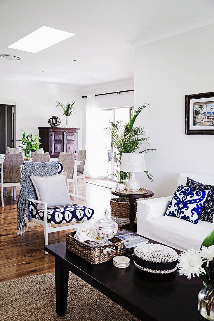 Offener Wohnbereich mit dunkelfarbenem Couchtisch und blau-weiß gemustertem Sessel
