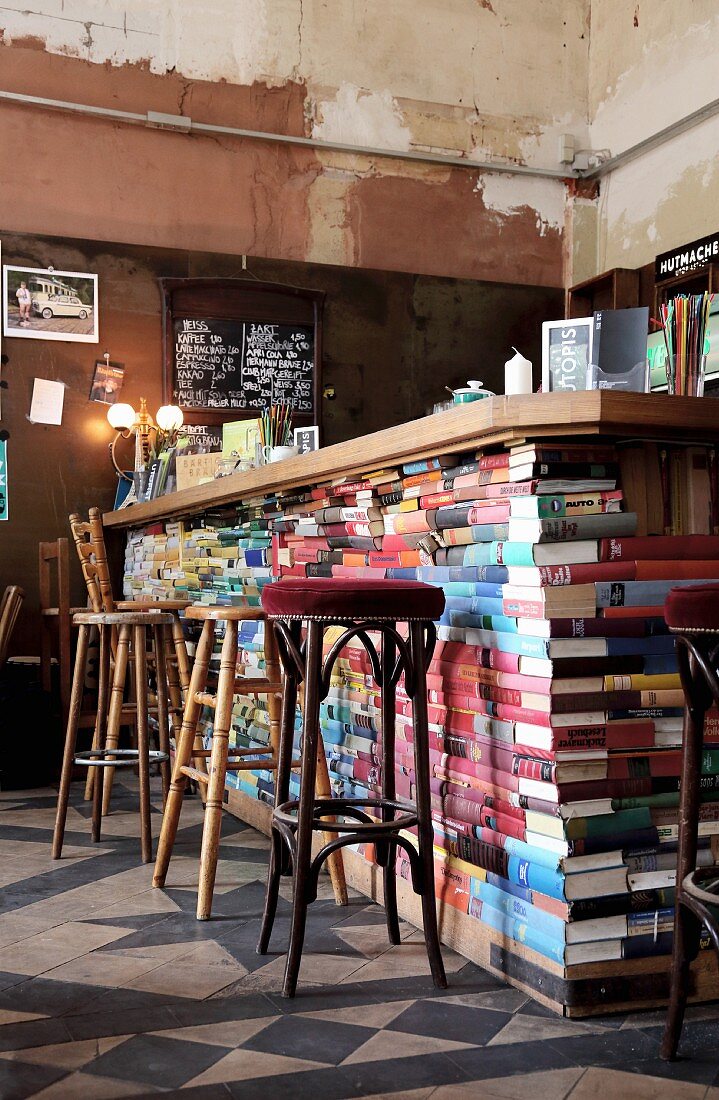Various barstools at counter made from old books in shabby-chic interior of Café Hutmacher, Wuppertal, Germany