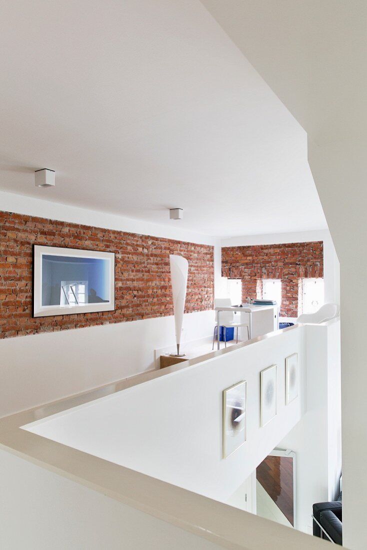 Gallery with exposed brick wall and standard lamp in office area at far end