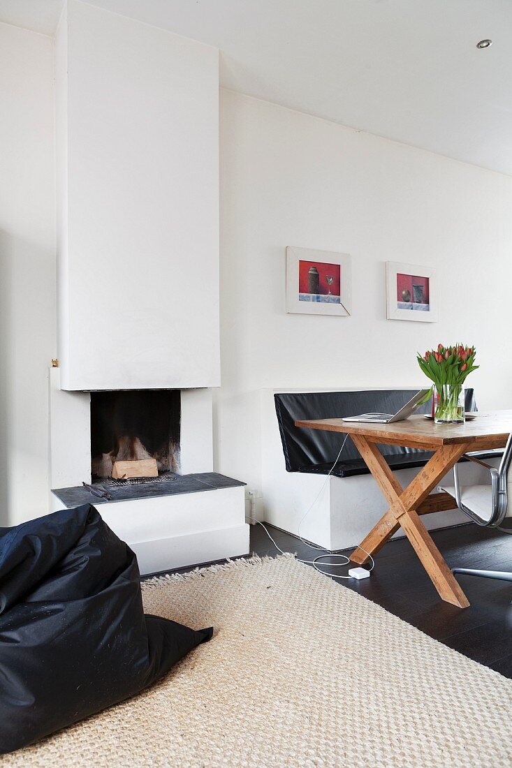 Wooden table and masonry bench next to open fireplace with black beanbag in foreground
