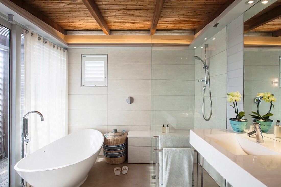Modern bathroom with free-standing white bathtub, shower area and reed ceiling