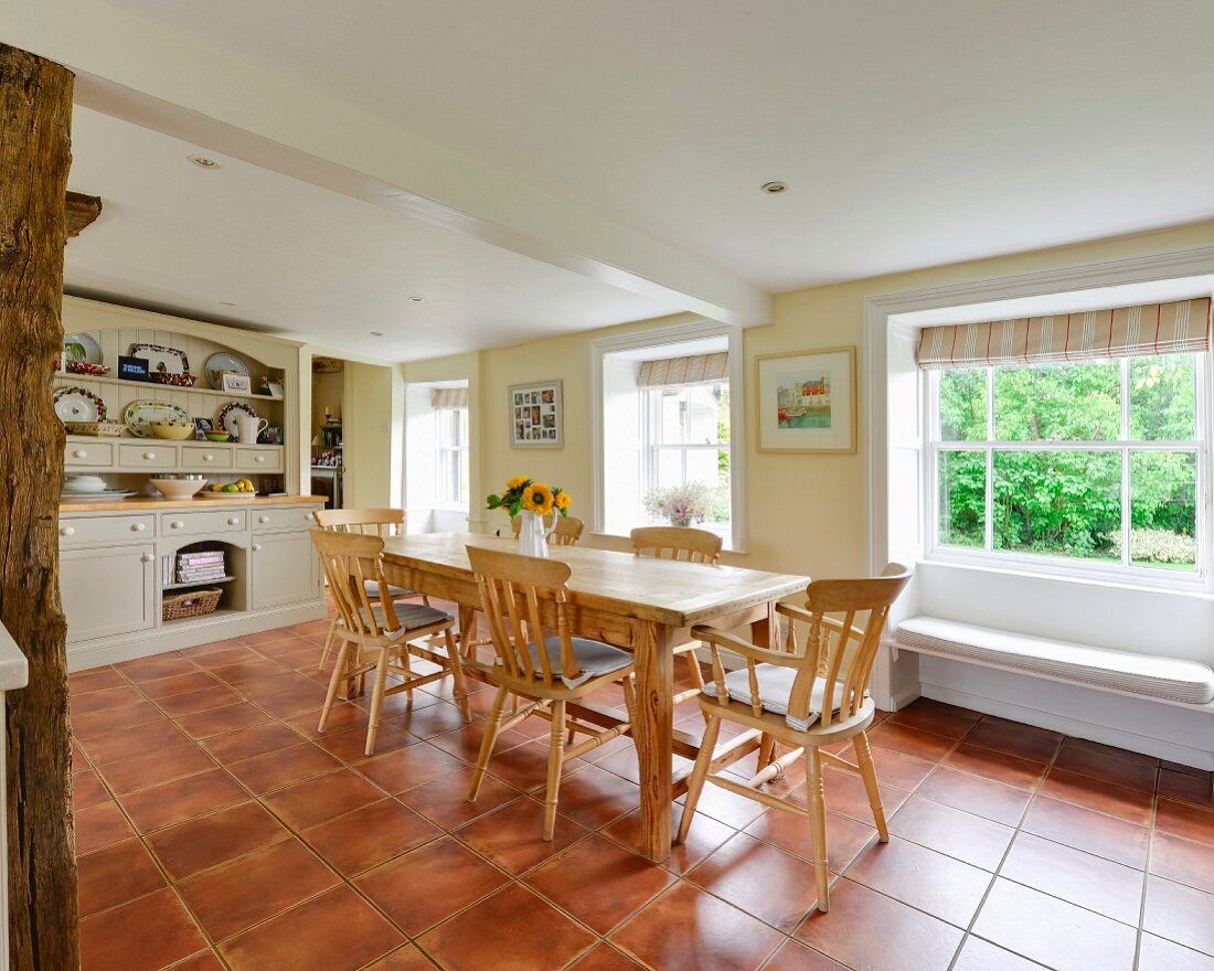 Rustikaler Esstisch mit Holzstühlen in ländlicher Küche mit Terrakottafliesenboden