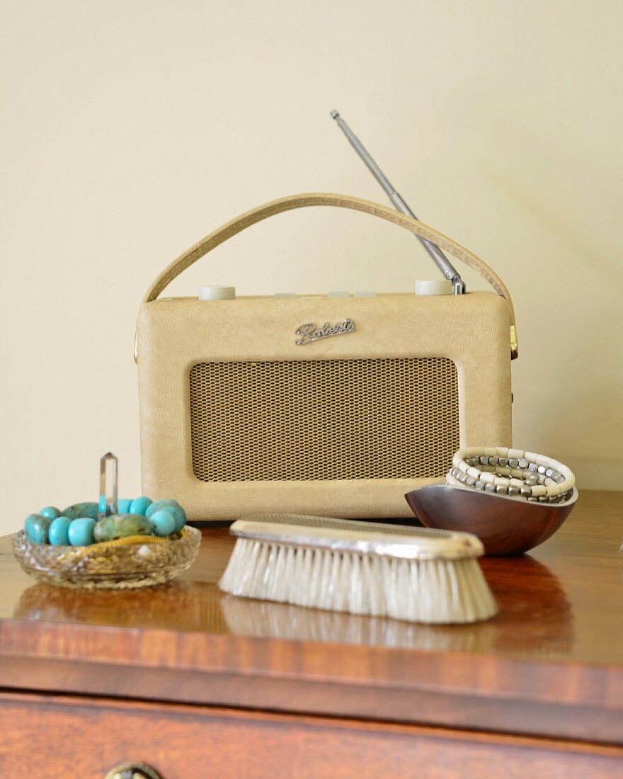 Schmuck in Schalen und Kleiderbürste vor Retro Kofferradio