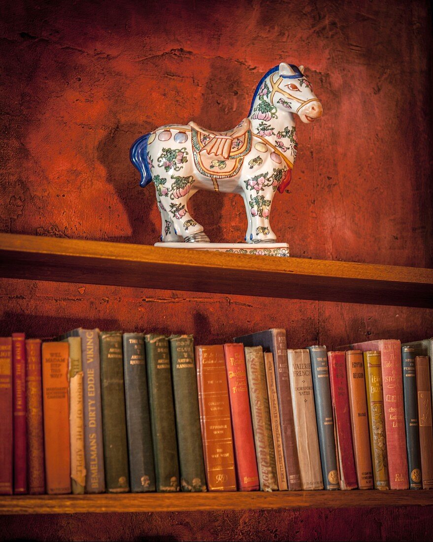 Antique ceramic horse on bookshelf