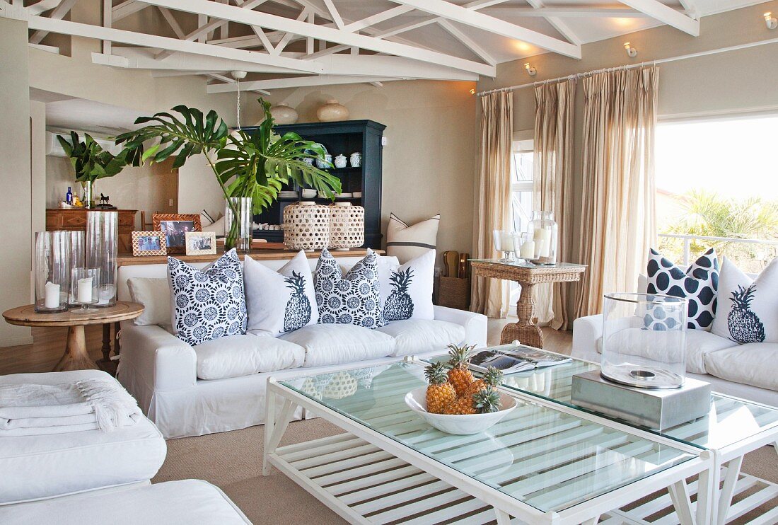 Offener Wohnbereich mit weißen Hussenmöbeln, lackierten Fachwerkträgern in elegantem Landhausambiente