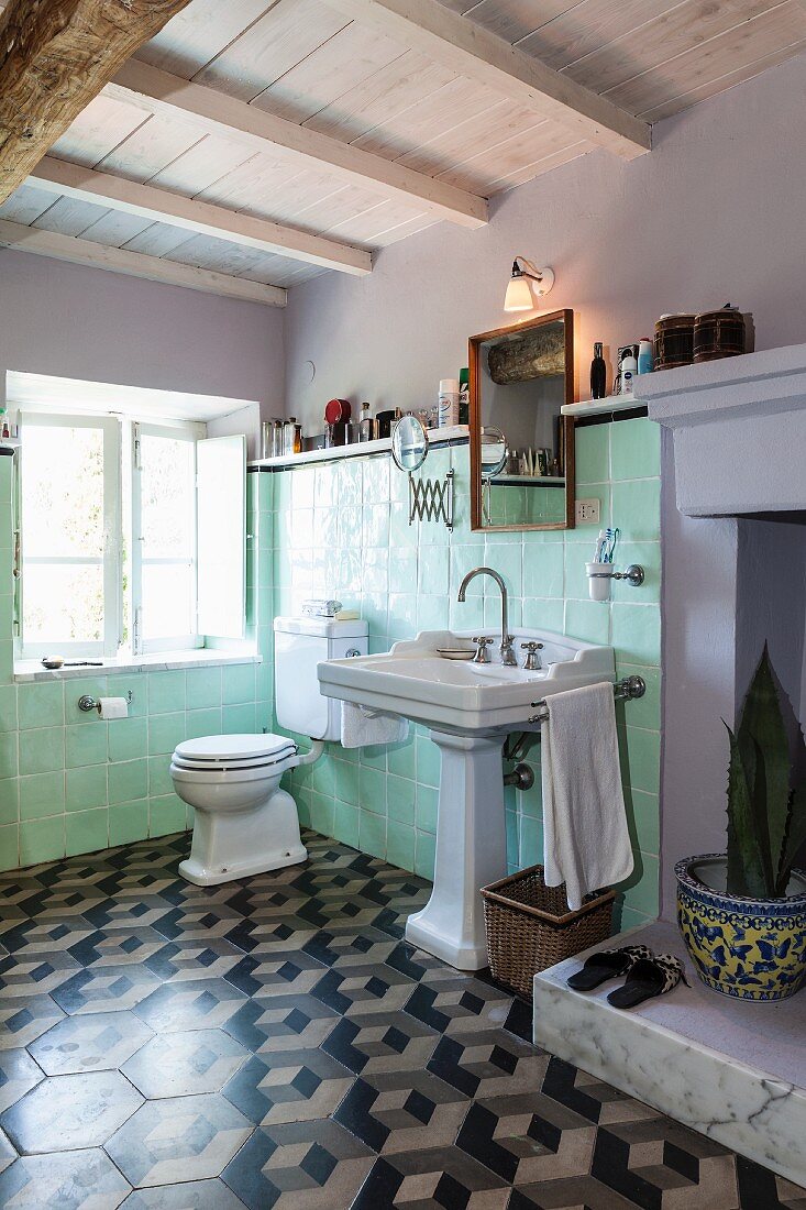 Pastel green wall tiles, pedestal sink and 3D-patterned floor tiles in vintage bathroom