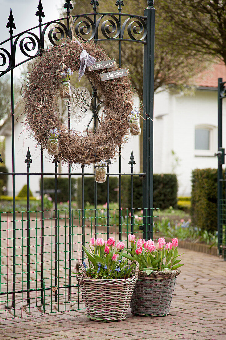 Wreath on wrought iron gate and baskets of spring flowers