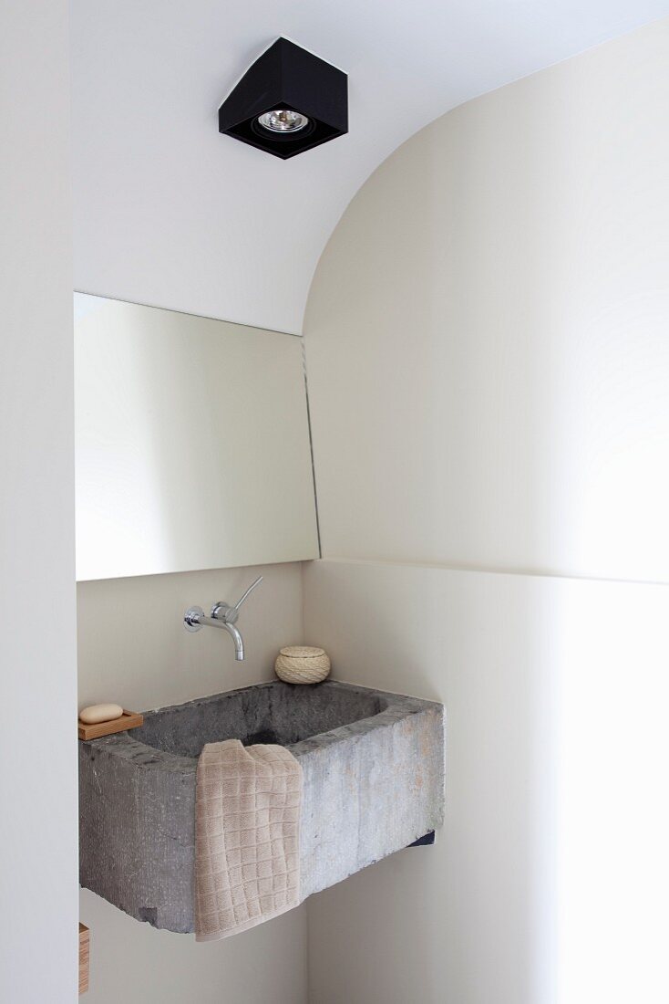 Rustic concrete sink in modernised bathroom with black ceiling lamp mounted on curved ceiling