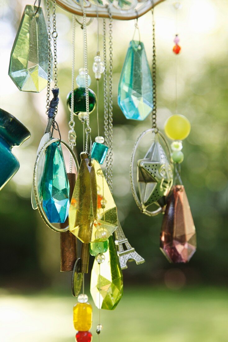 Glitzernde Kristallanhänger und Dekoperlen an DIY-Windspiel im Garten