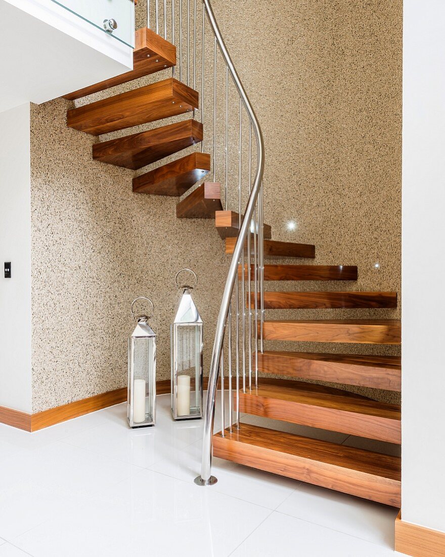 Gewendelte Treppe mit Holzstufen und Edelstahl-Geländer, Laternen auf Fliesenboden