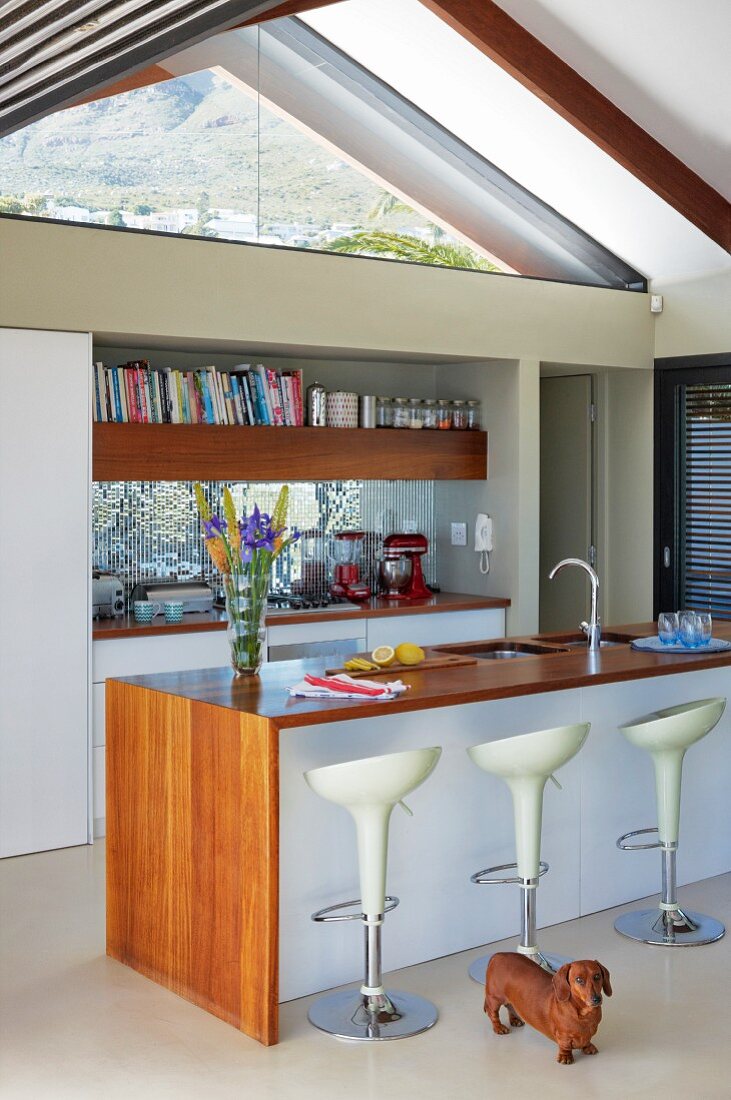 weiße Designer-Barhocker vor freistehender Küchentheke, mit Holzdeckplatte, in offener Küche