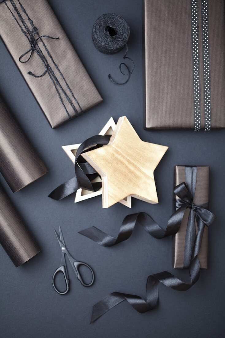 Sternförmige Schachtel, umgeben von Geschenkpäckchen und grauen Einpack-Utensilien