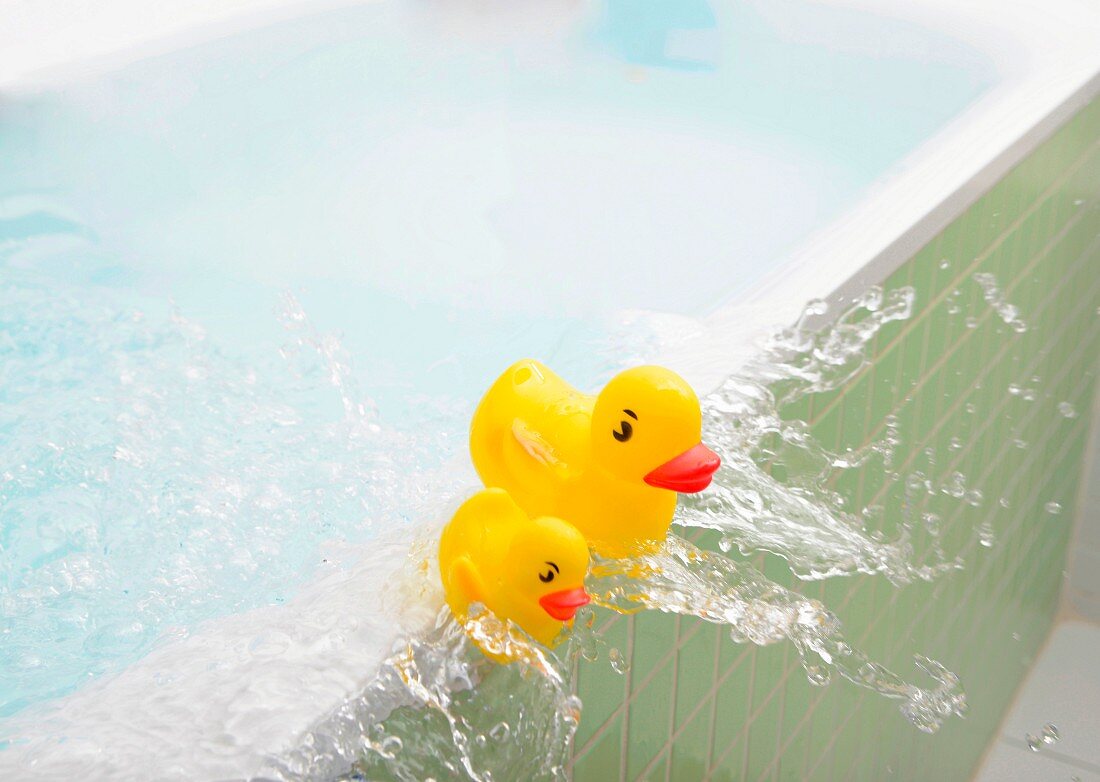 Gelbe Badeenten schwimmen mit überschwappendem Wasser aus der Badewanne