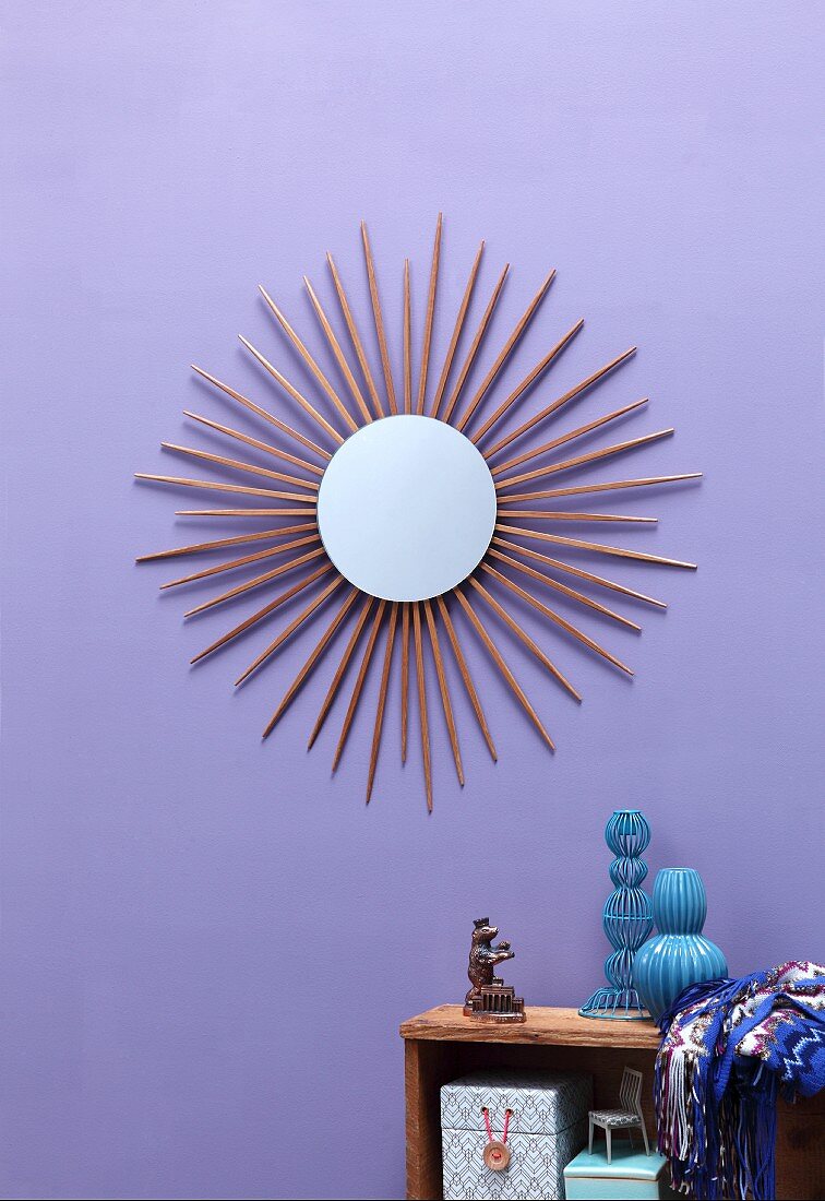 Runder Wandspiegel mit strahlenförmigem Rahmen aus Essstäbchen an lilafarbener Wand