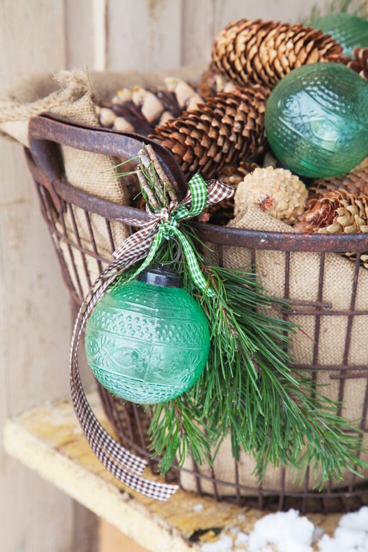 Pine cones and green baubles in metal basket