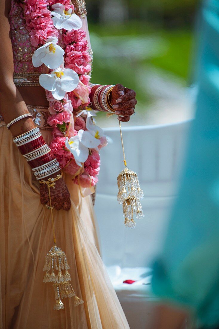 Indische Hochzeit - geschmückte Frau mit Blumengirlande und Hochzeitsdeko in Händen
