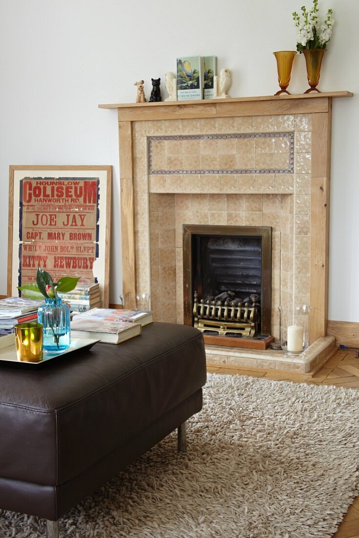 Open fireplace with tiled surround in traditional interior with modern ottoman