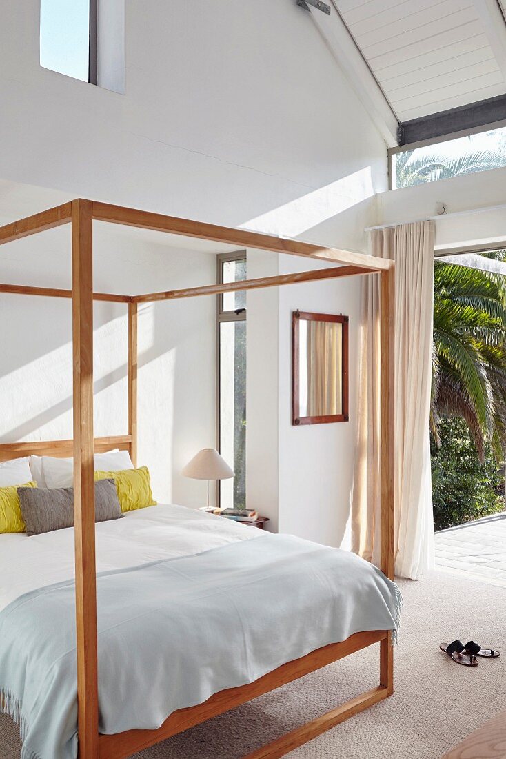 Himmelbett mit Holzgestell in Schlafzimmer mit offener Terrassentür