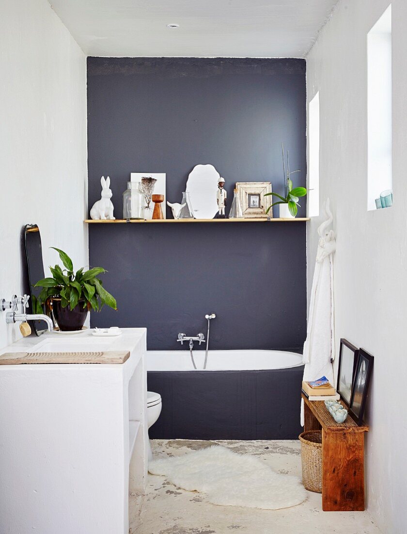 Minimalistisches Bad mit dunkelgrauer Wand und Regalbrett, davor gemauerter Waschtisch