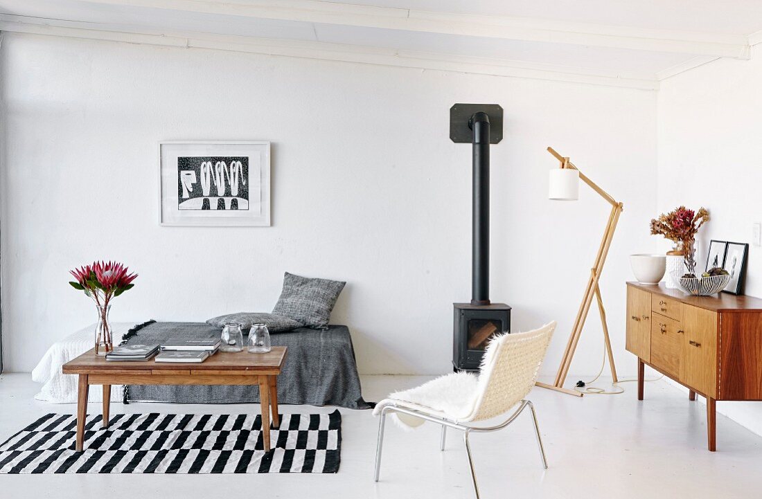 Minimalistisches Wohnzimmer mit Couchtisch auf schwarz-weiss gestreiftem Teppichläufer vor Tagesliege und weißem Stuhl