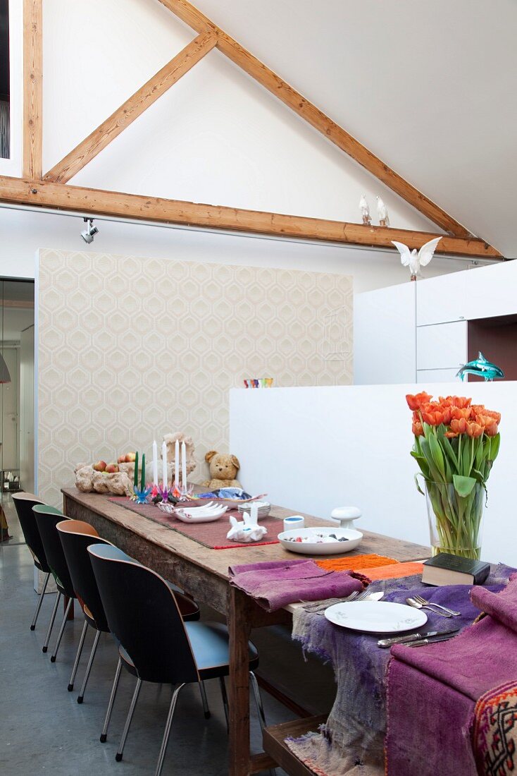 Long dining table in loft apartment with exposed roof structure