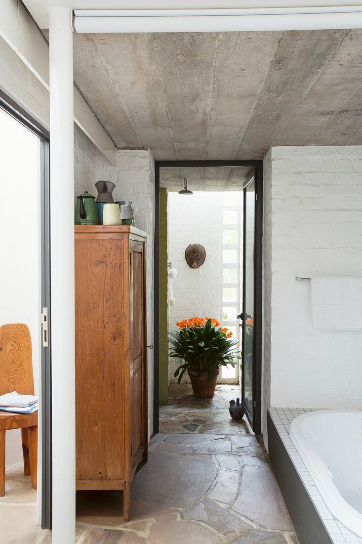 Badezimmer mit Betondecke, Backsteinwand und Natursteinboden