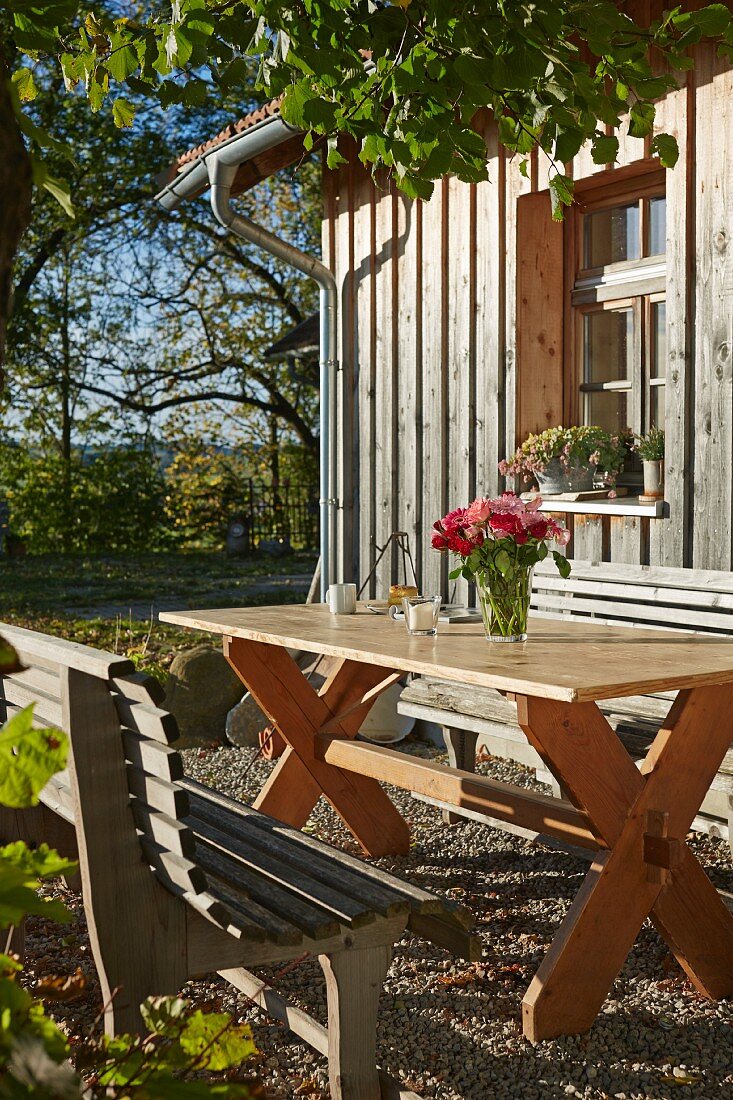 Rustic seating area in autumn sunshine outside wooden house
