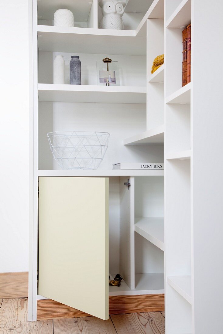 White, custom-made corner shelves with open cupboard door