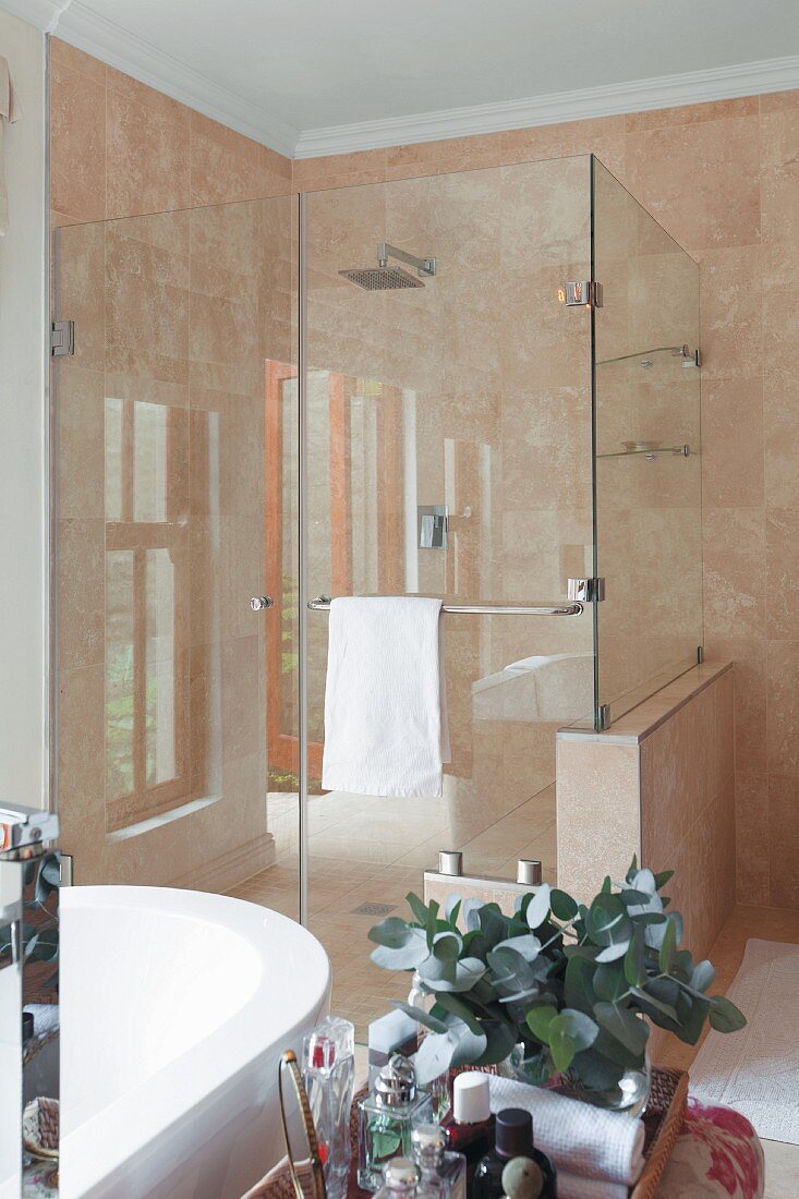 Blick auf verglasten Duschbereich, Wände mit marmorierten Fliesen belegt