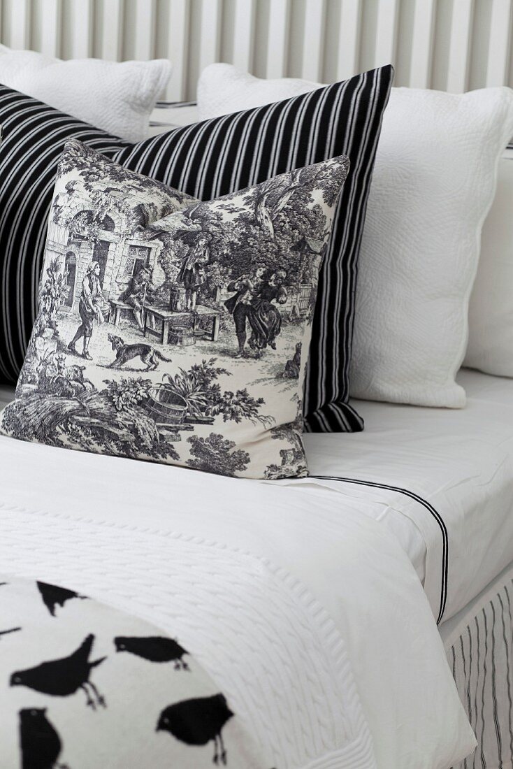 Black and white patterned scatter cushions arranged on bed