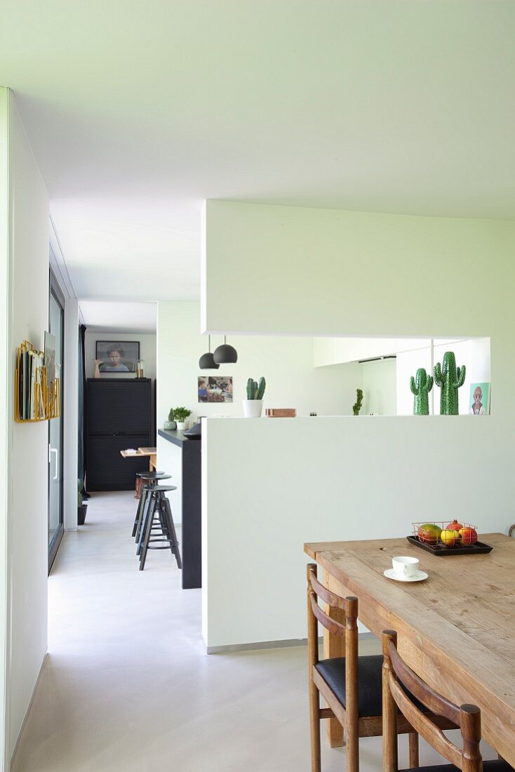 Blick vom Essbereich auf offenen Küchenbereich mit modernem Wandausschnitt und Durchgang
