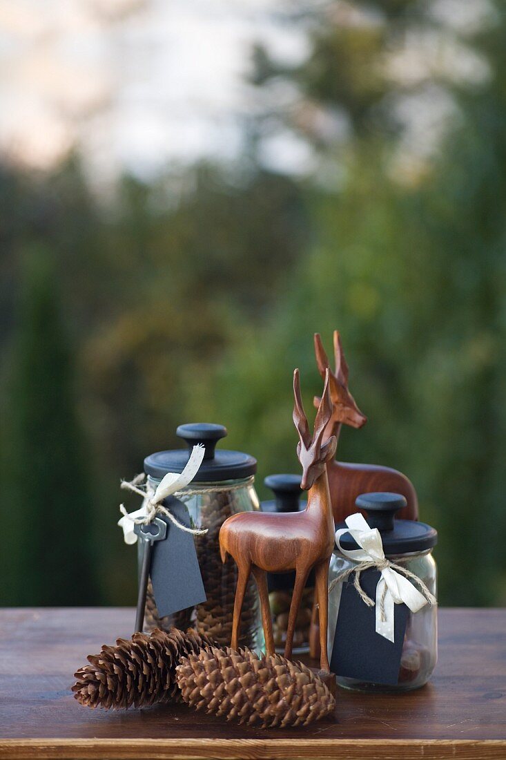 Autumn arrangement of storage jars with black lids and labels, wooden antelopes and pine cones