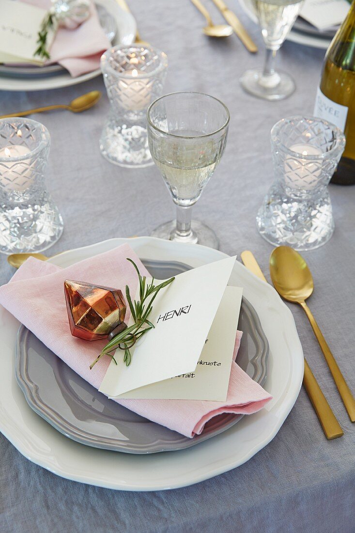 An elegant placecard menu with a a sprig of rosemary and a tree decoration