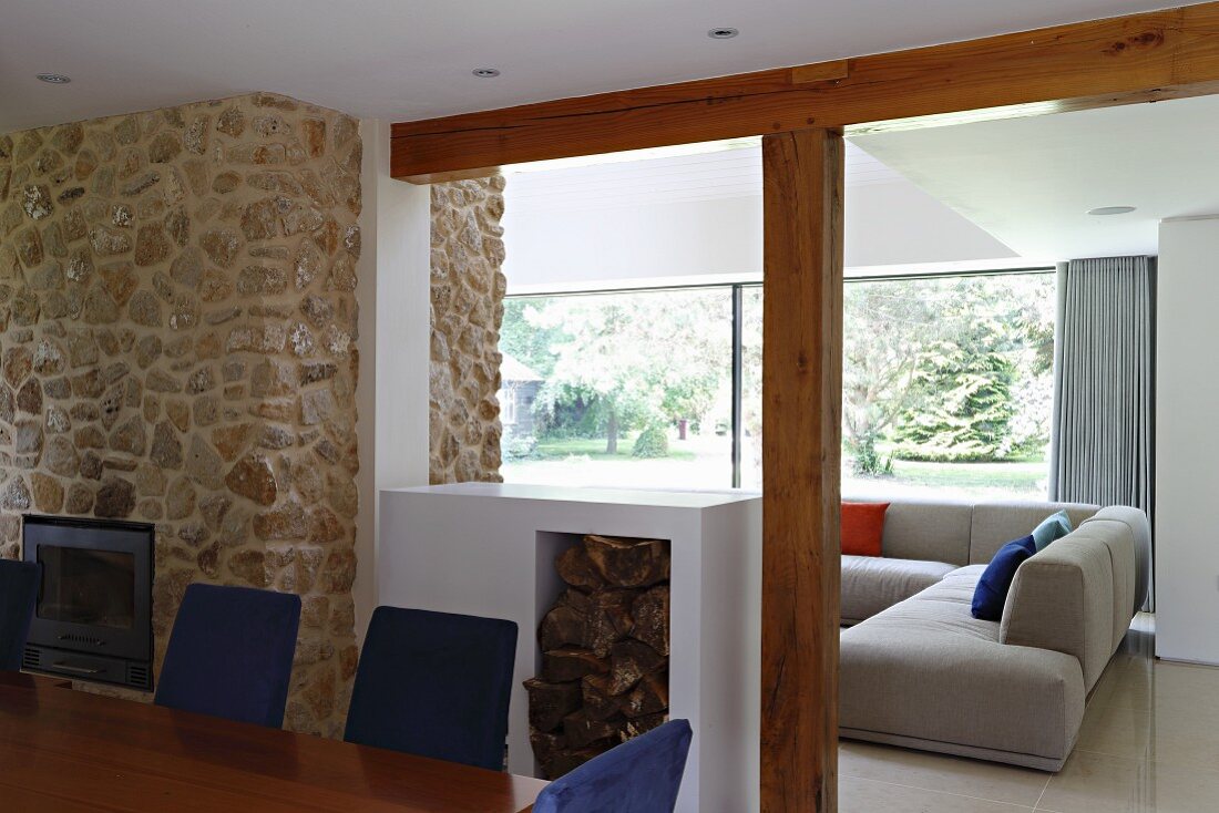View across dining table and half-height firewood store into lounge area