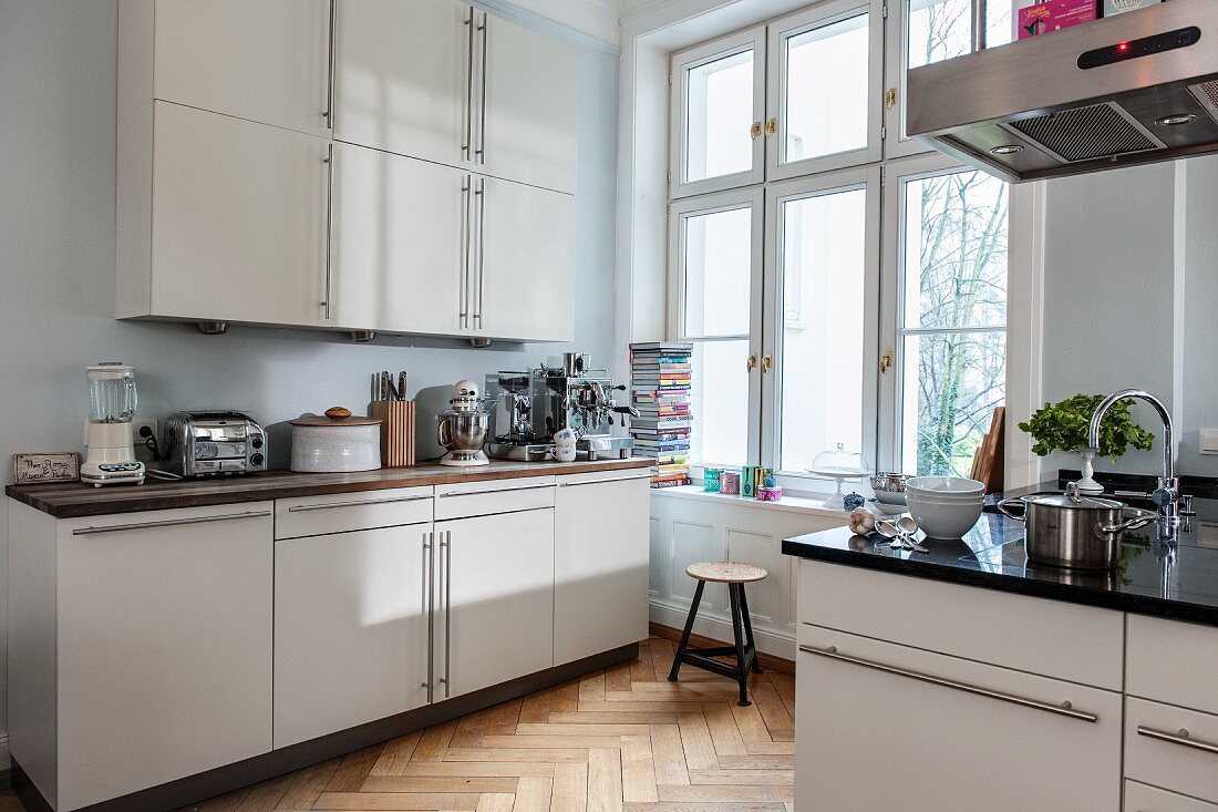 Fitted kitchen with white doors and herringbone parquet floor in period apartment