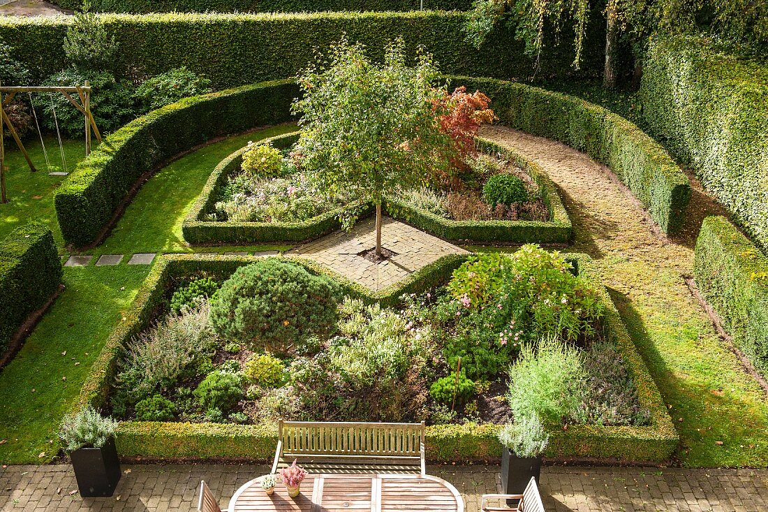 Blick von oben auf eleganten Garten mit formgeschnittenen Hecken um Staudenbeete