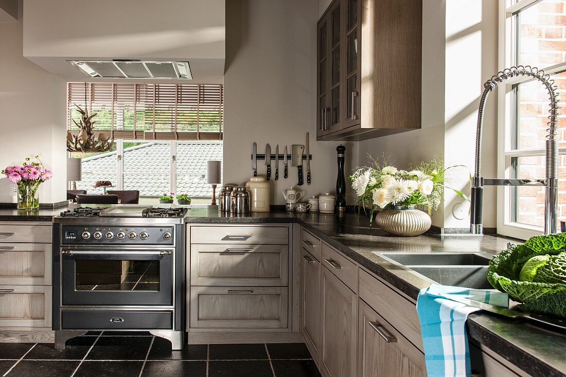 Einbauküche mit hellen Holzfronten, im Hintergrund Durchreiche und Blick auf Fenster