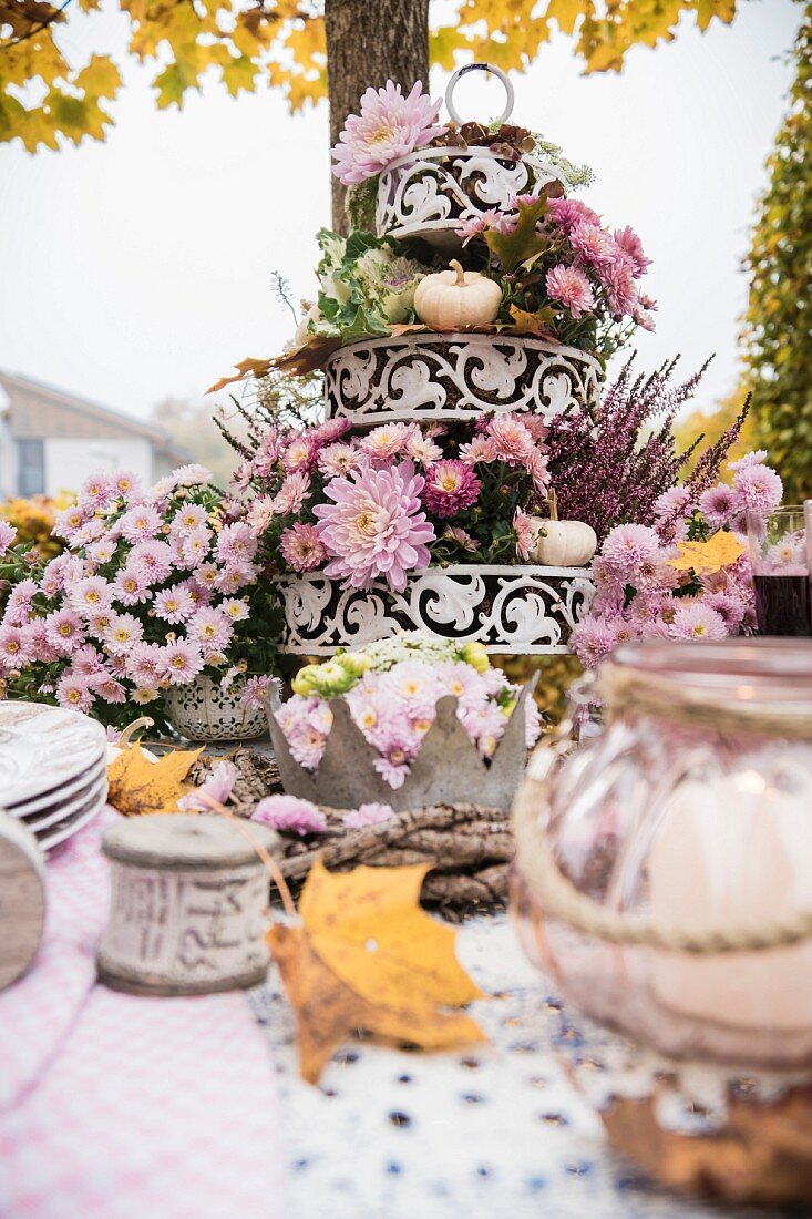 Herbstlich gedeckter Tisch mit einer Etagere voller Blumen