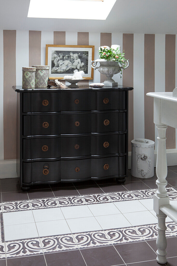 Black-painted chest of drawers against striped wallpaper in vintage-style bathroom