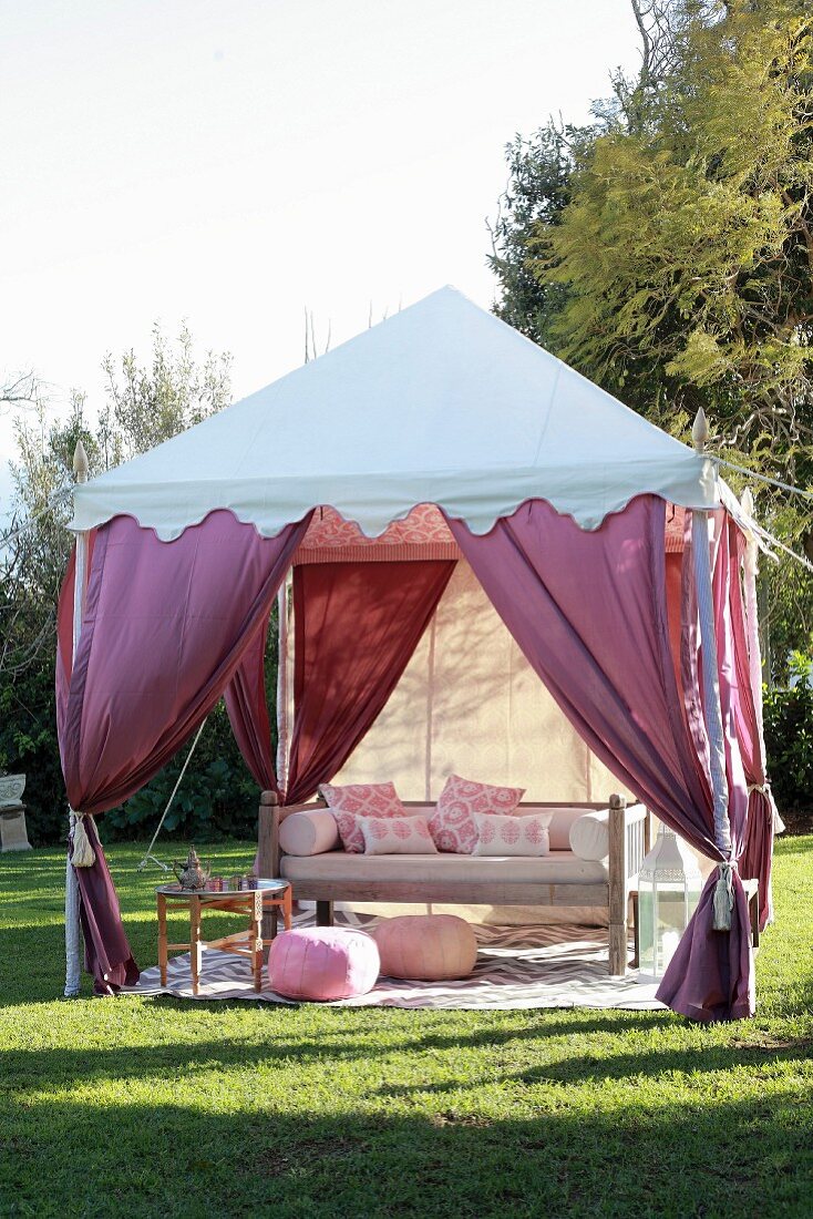 Schattiger Platz im Garten im Stil eines Beduinenzeltes mit drapierten Vorhängen in Violetttönen