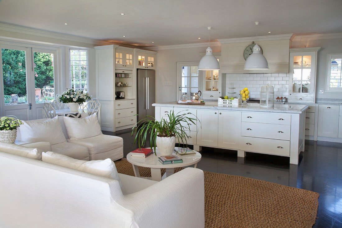 Open-plan interior with white sofa set and free-standing kitchen counter