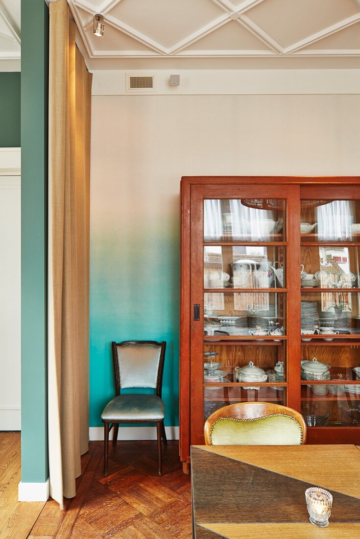 Table in front of display case against turquoise and white ombré-effect wall